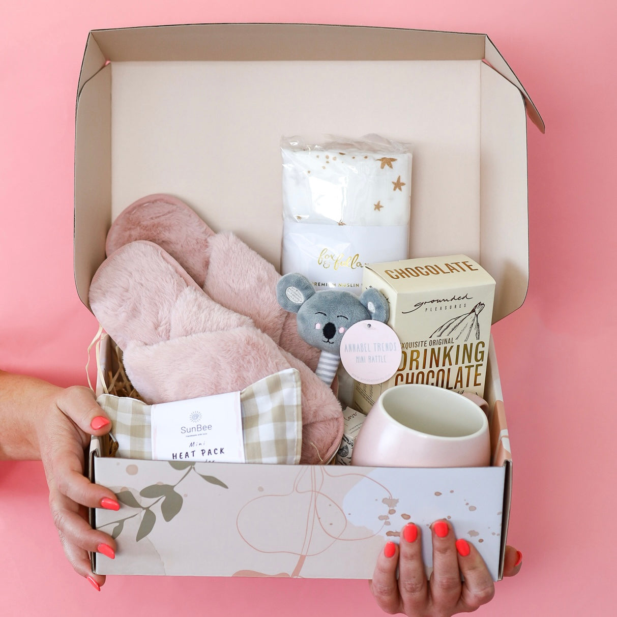 gift box for new mum and new baby. contains heat pack, slippers, mug, drink, baby blanket and rattle 